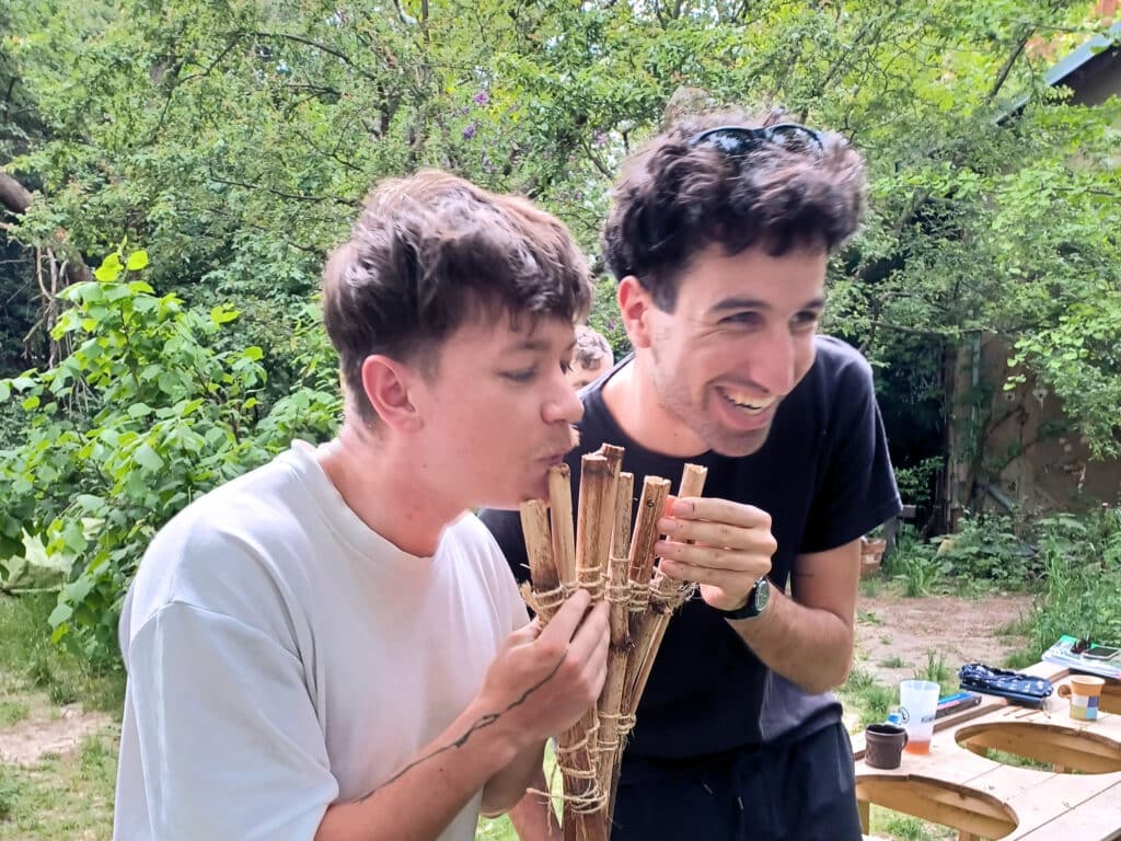 Two people holding a pan flute