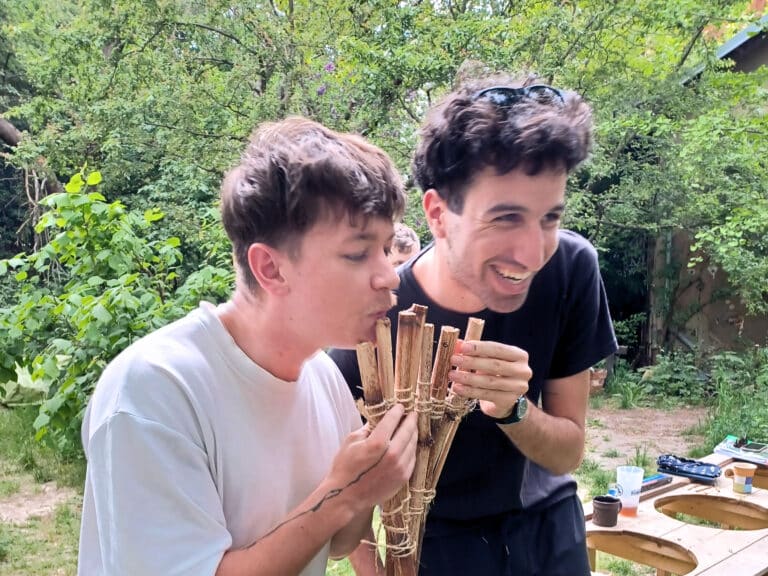 Two people holding a pan flute