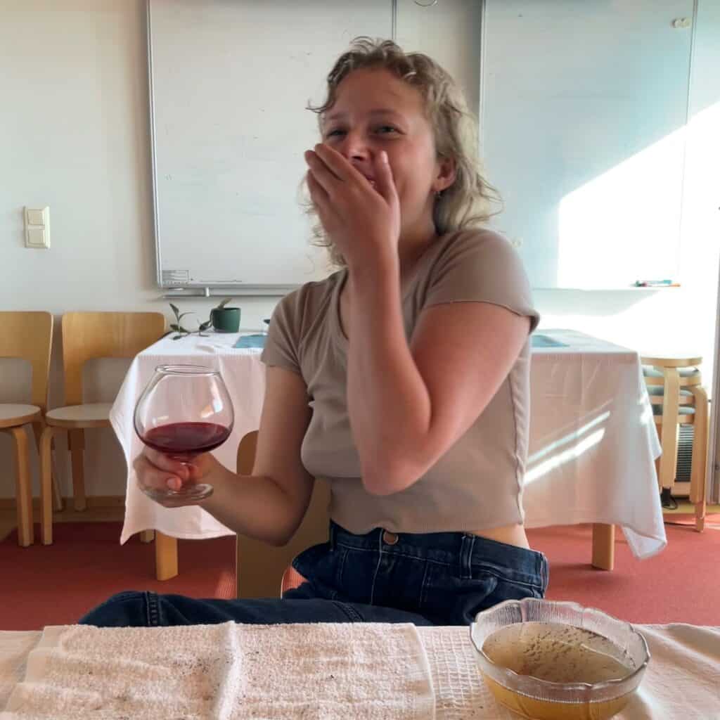 person laughing and holding a glass of wine