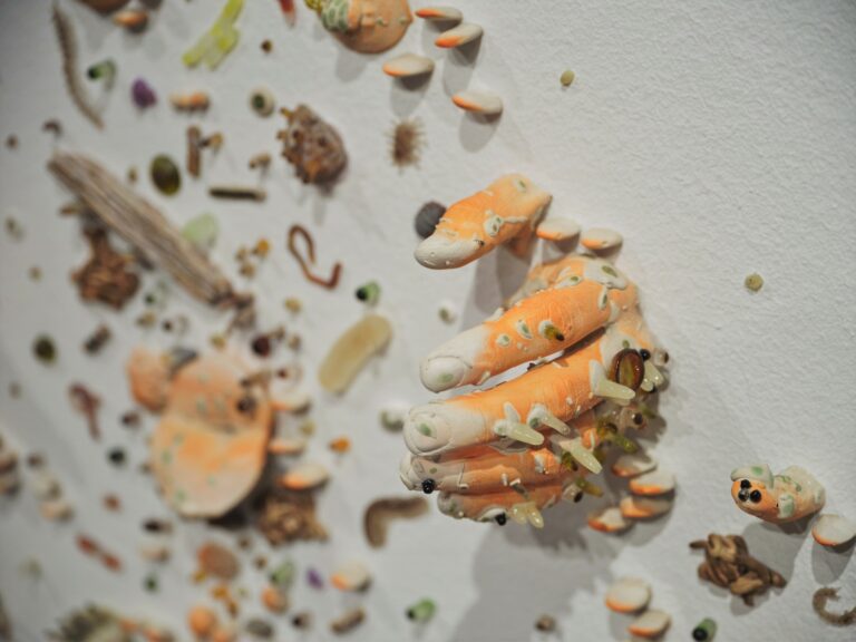 close up of an art piece with fingers and small creatures on a wall