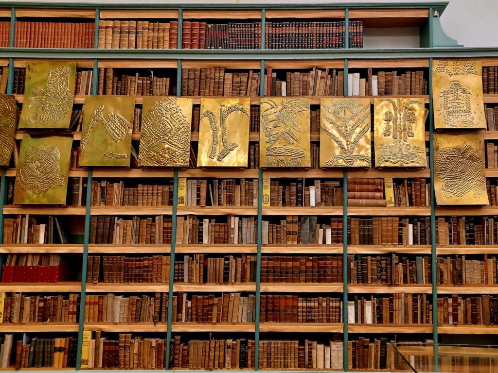 brass art pieces hanging from a large bookcase